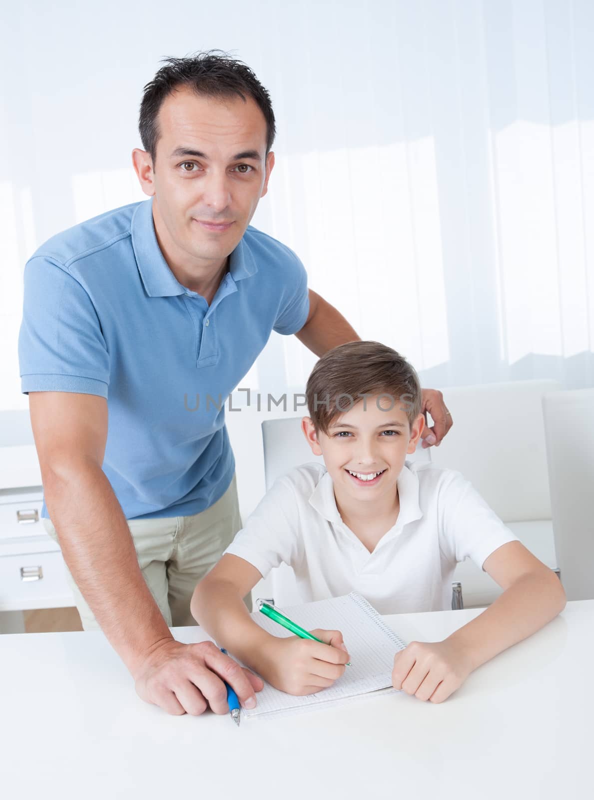 Portrait Of A Boy Doing Homework With His Father At Home