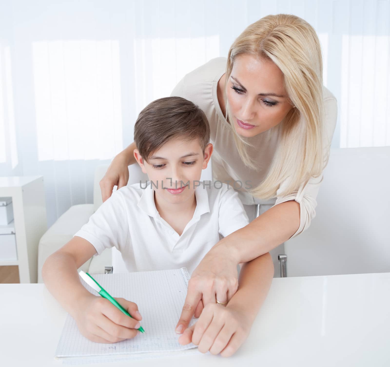 Teacher Helping Boy With Exercise At School