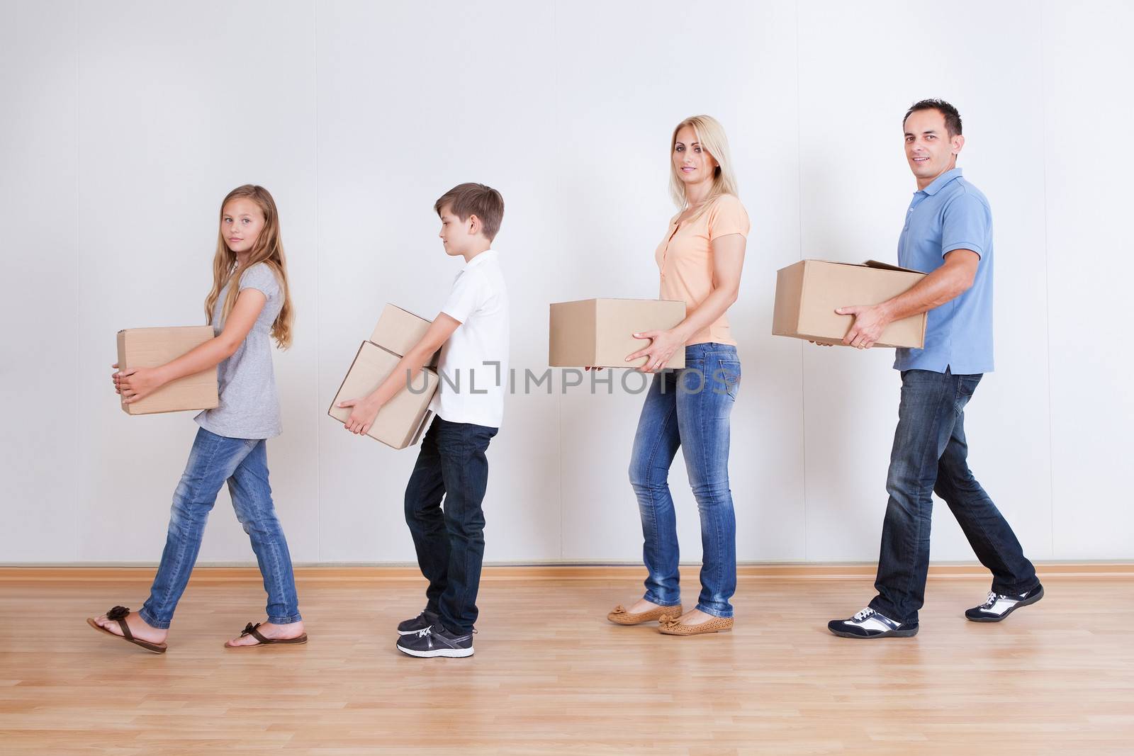 Parents And Two Children With Cardboard Boxes, Indoors