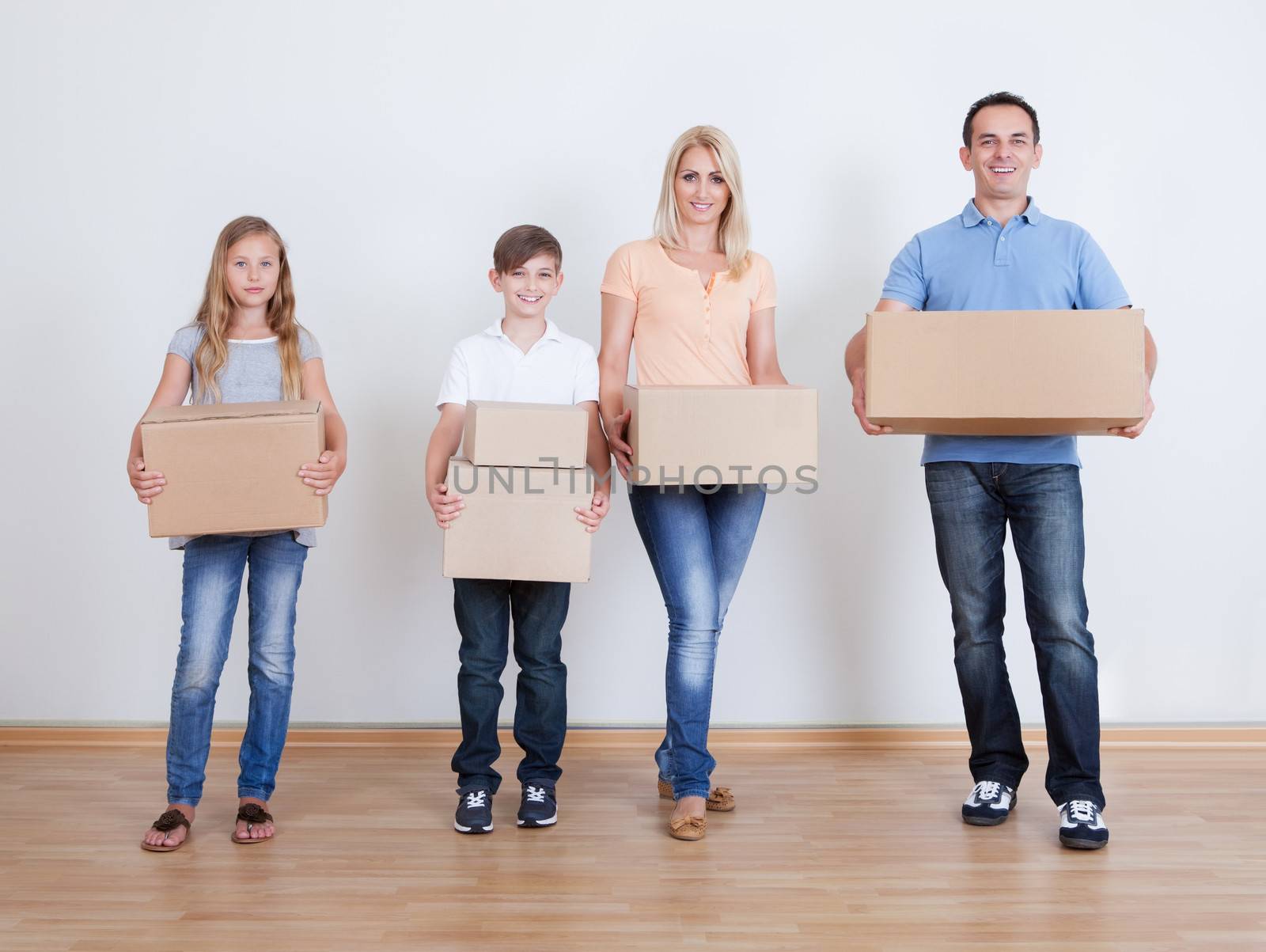 Parents And Two Children With Cardboard Boxes, Indoors