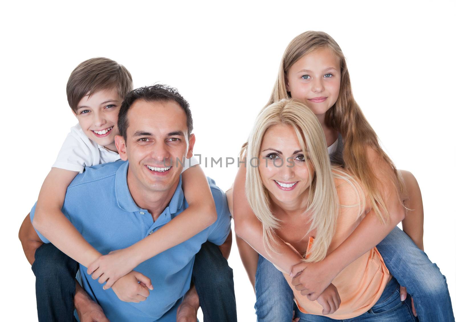 Couple Giving Two Young Children Piggyback Rides Isolated On White Background