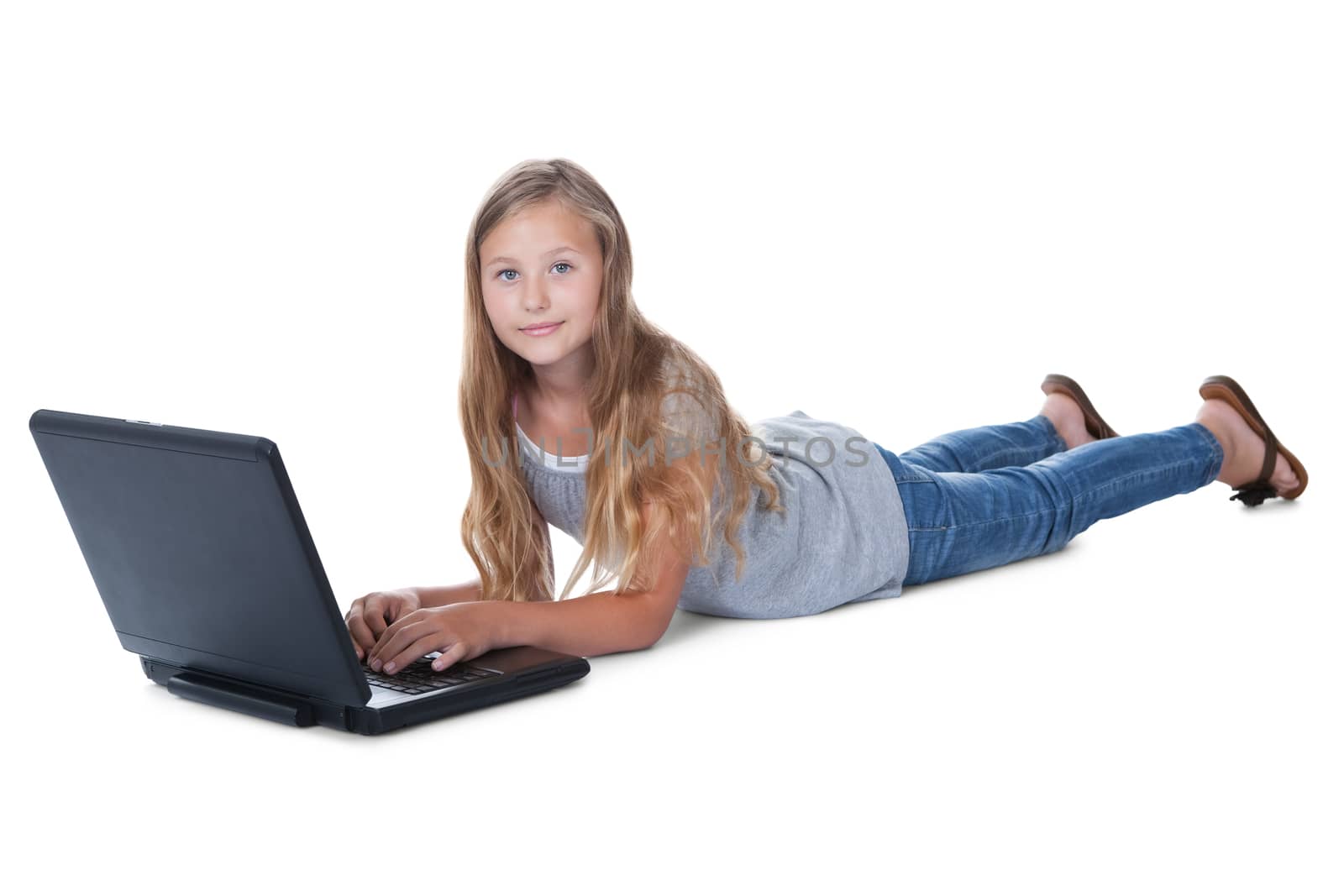 Little Girl Lying On Floor Using A Laptop Isolated On White Background