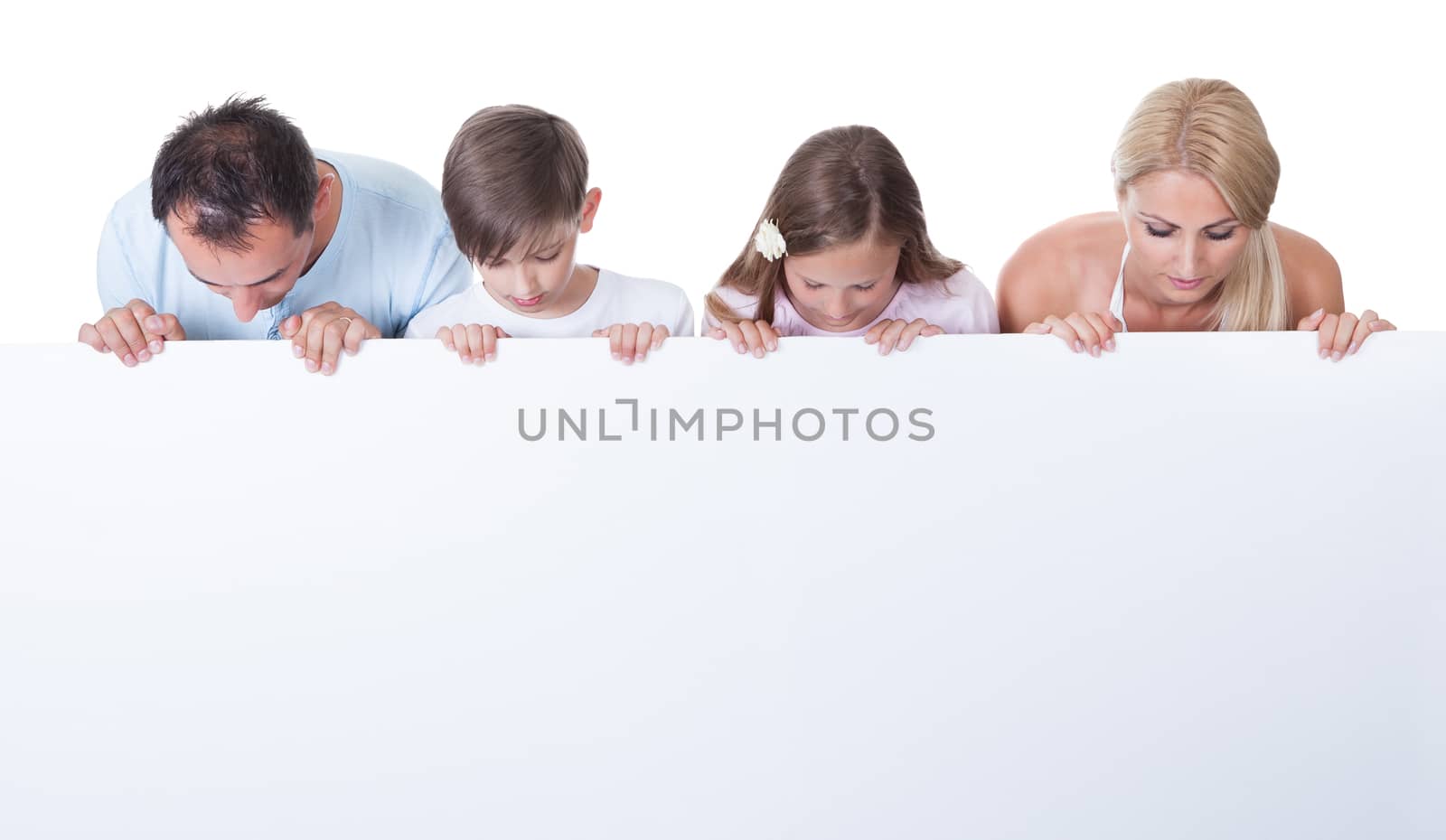 Portrait Of Family With Two Children Behind Blank Board On White Background