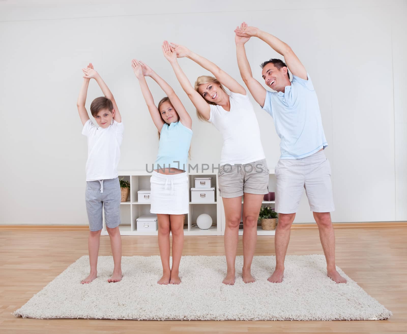 Family Doing Stretching Exercises On The Carpet At Home