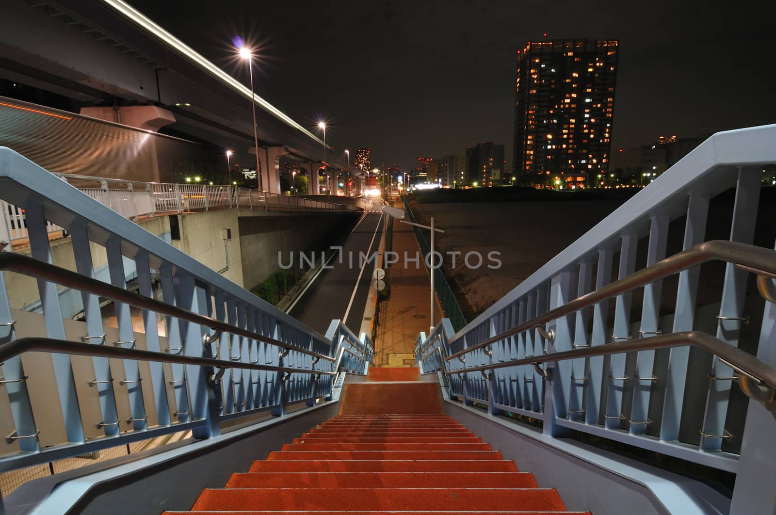 illuminated stairs going down near huge highway in night city