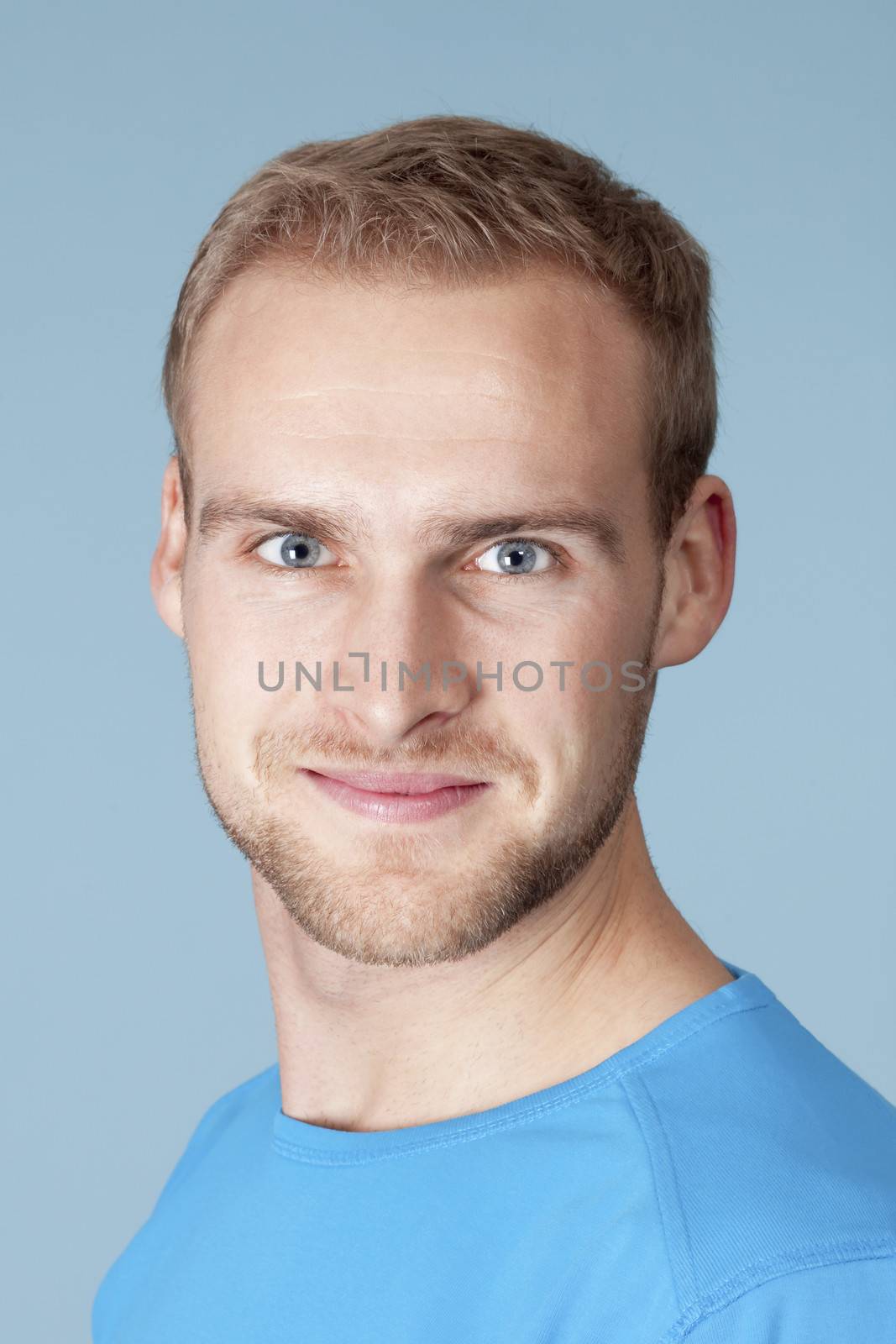 portrait of a young man with blond hair - isolated on blue