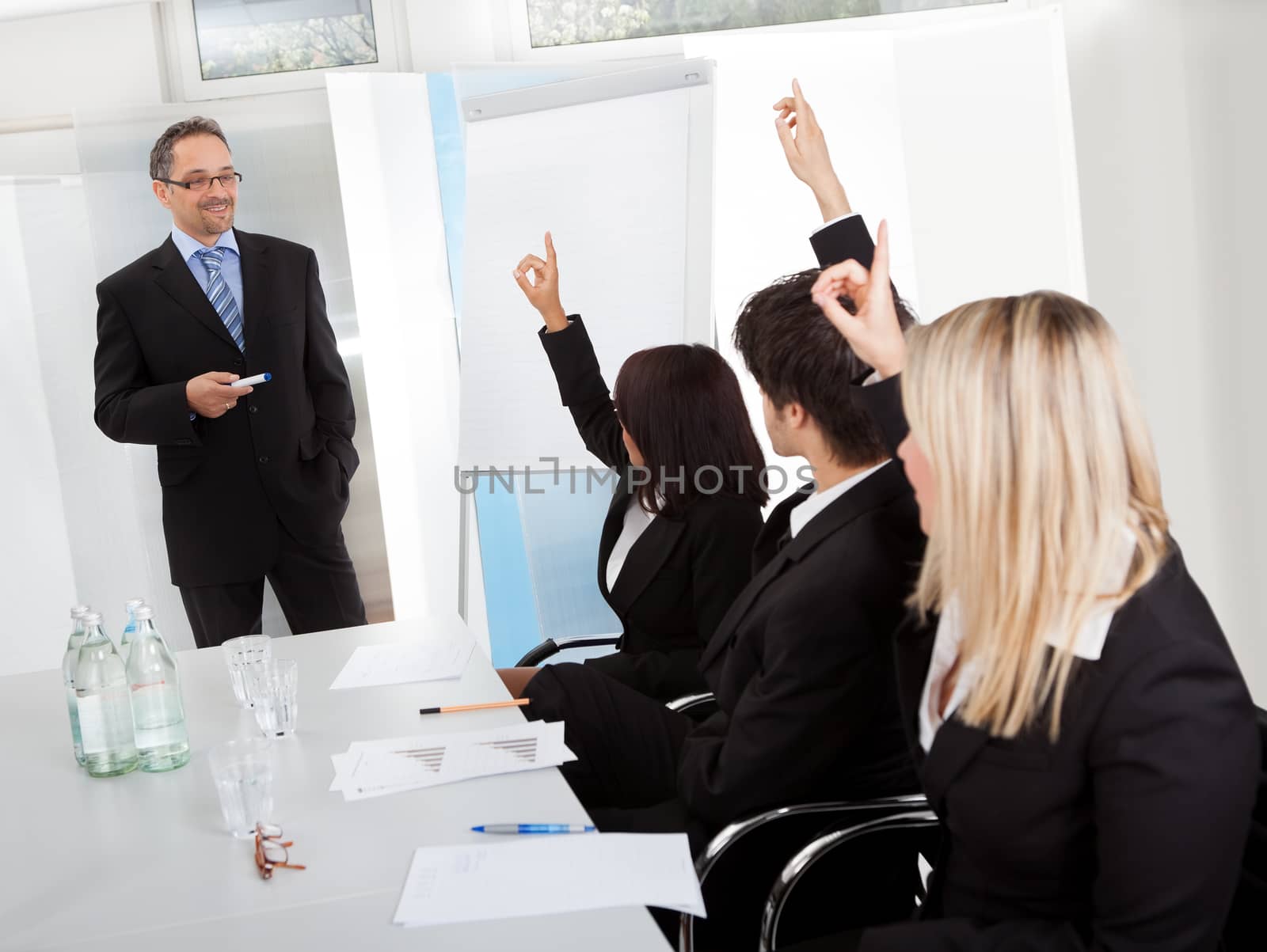 Business people at presentation raising hands by AndreyPopov