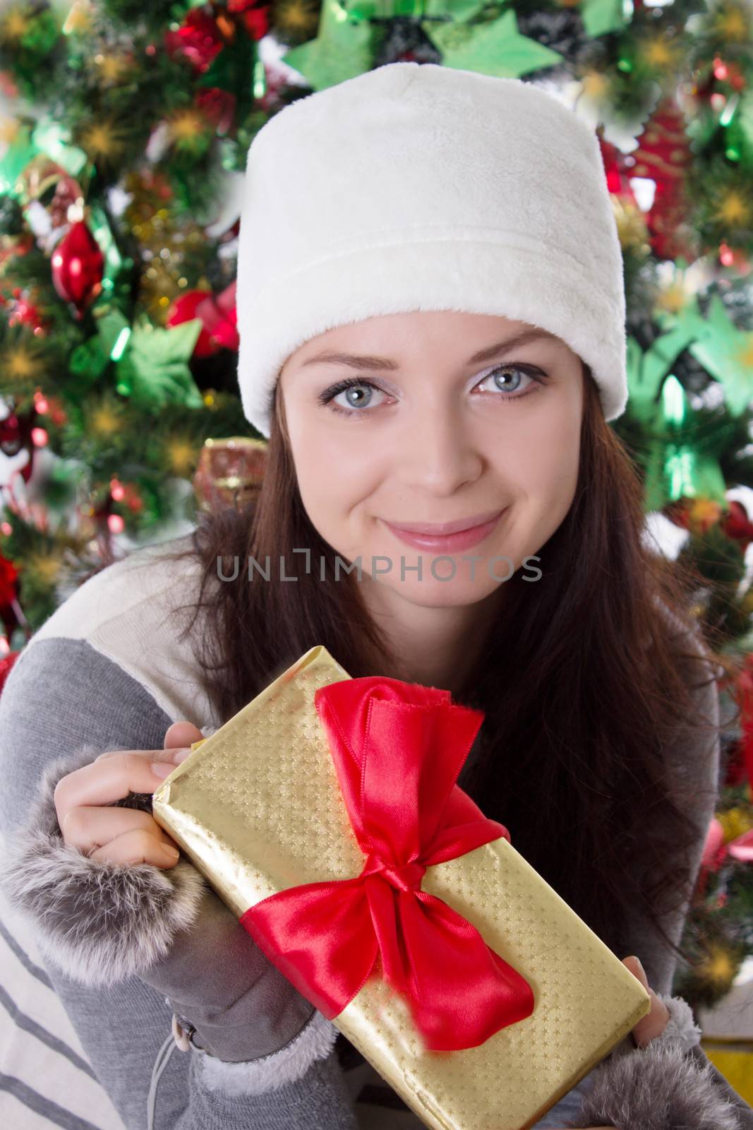 Smiling woman in fur hat and mitten holding Christmas present