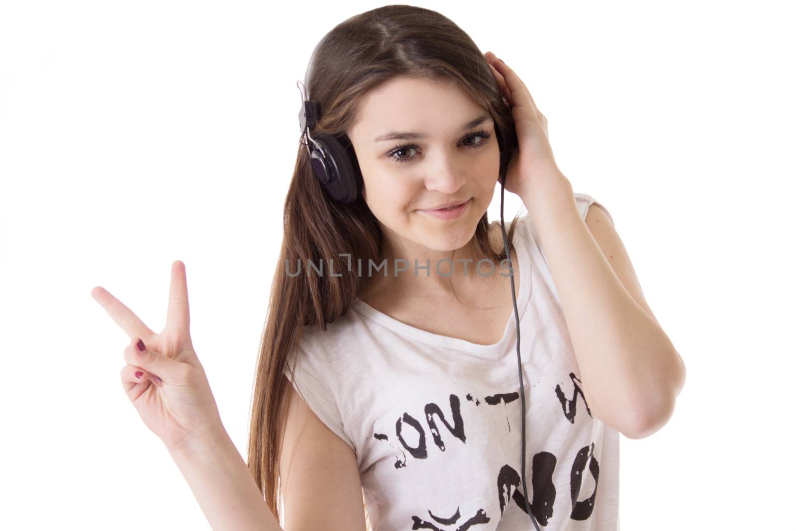 Joyful teen girl with headphones showing victory sign over white