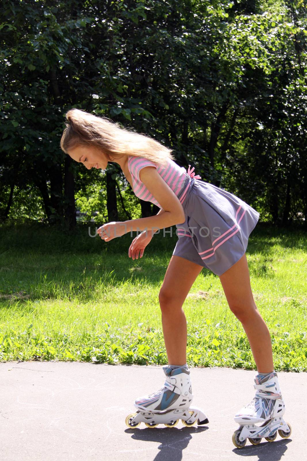 Happy young woman enjoying roller skating rollerblading on inline skates sport in park. Woman in outdoor activities