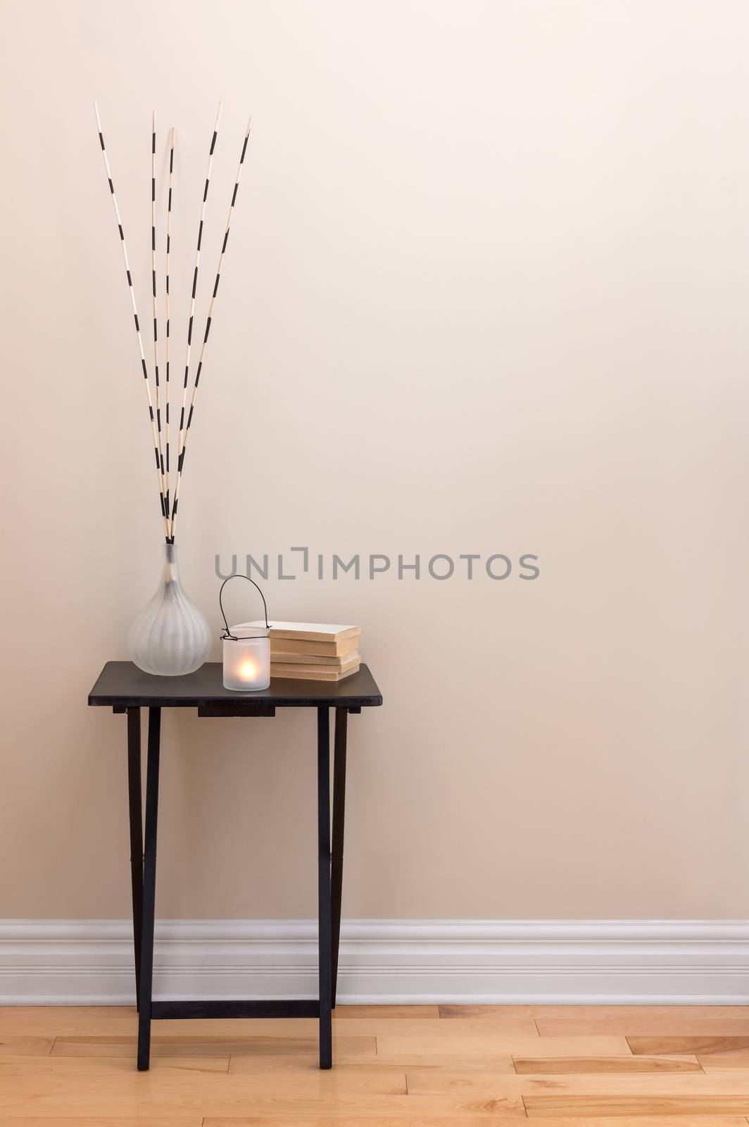 Home decor. Little table decorated with candlelight, vase and books.