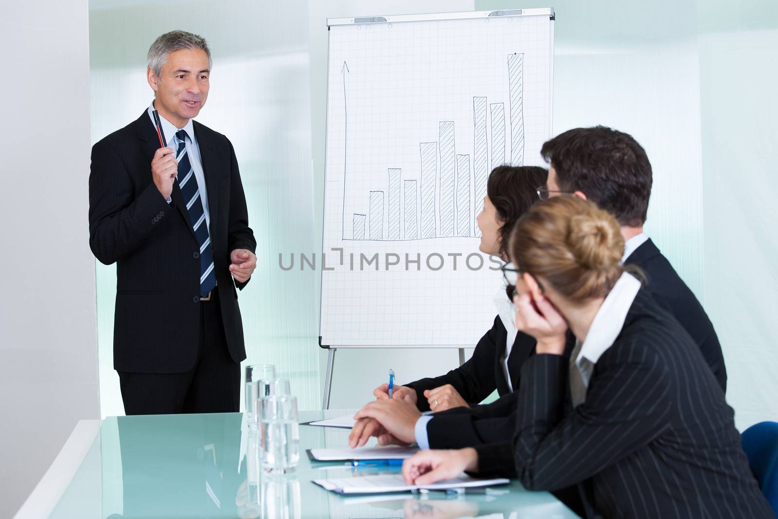 A senior business executive delivering a presentation to his colleagues during a meeting or in-house business training