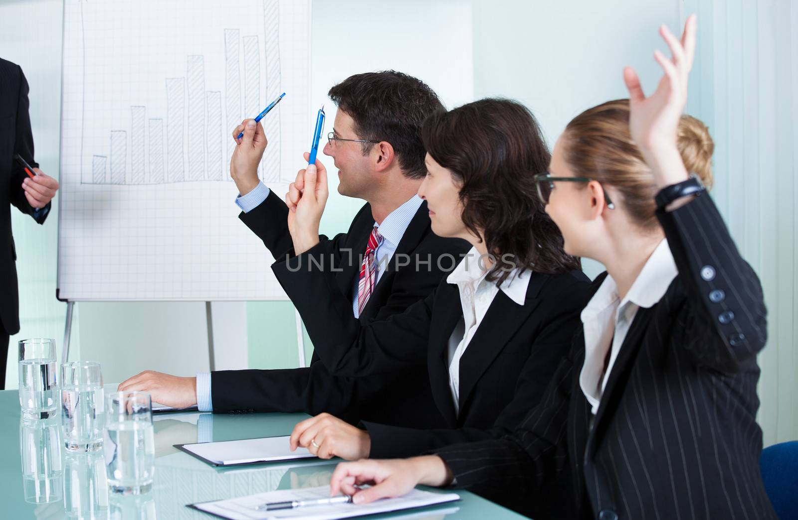 Manager or senior business executive standing in front of a graph giving a presentation to staff or colleagues seated at a table