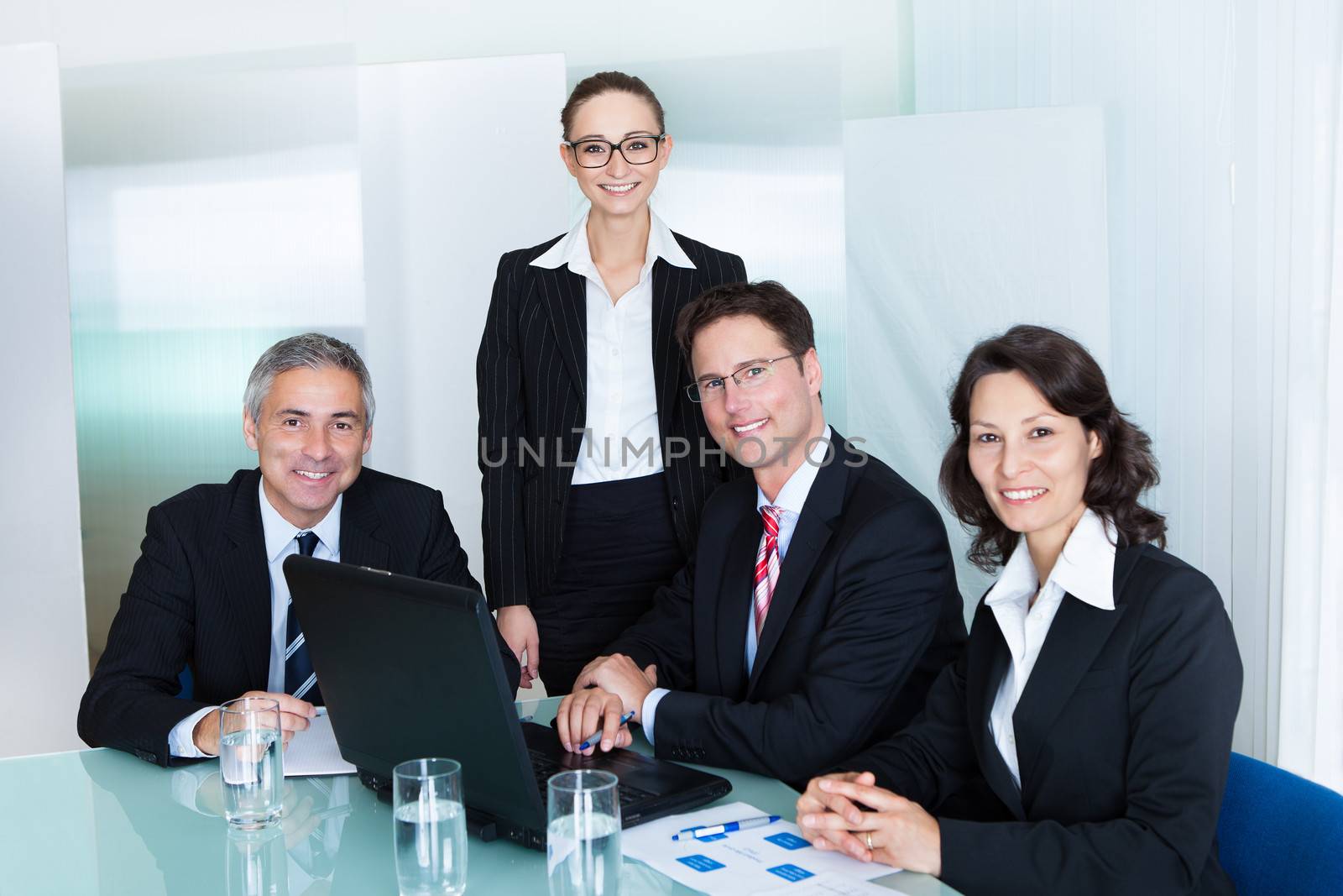 Business team of professional men and women have a meeting gathered around a laptop computer surrounded by literature