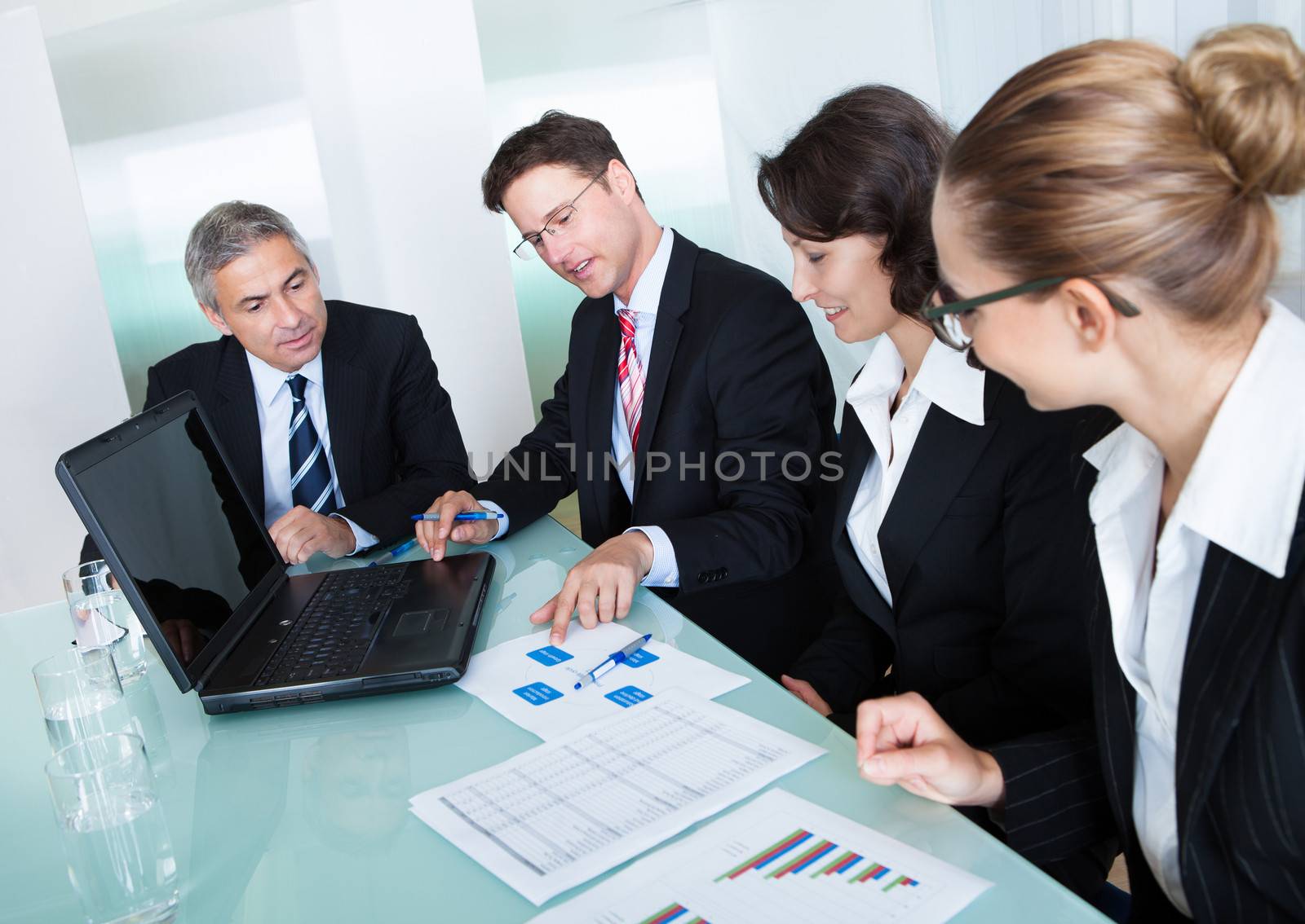 Group of diverse business executives holding a meeting around a table discussing graphs showing statistical analysis