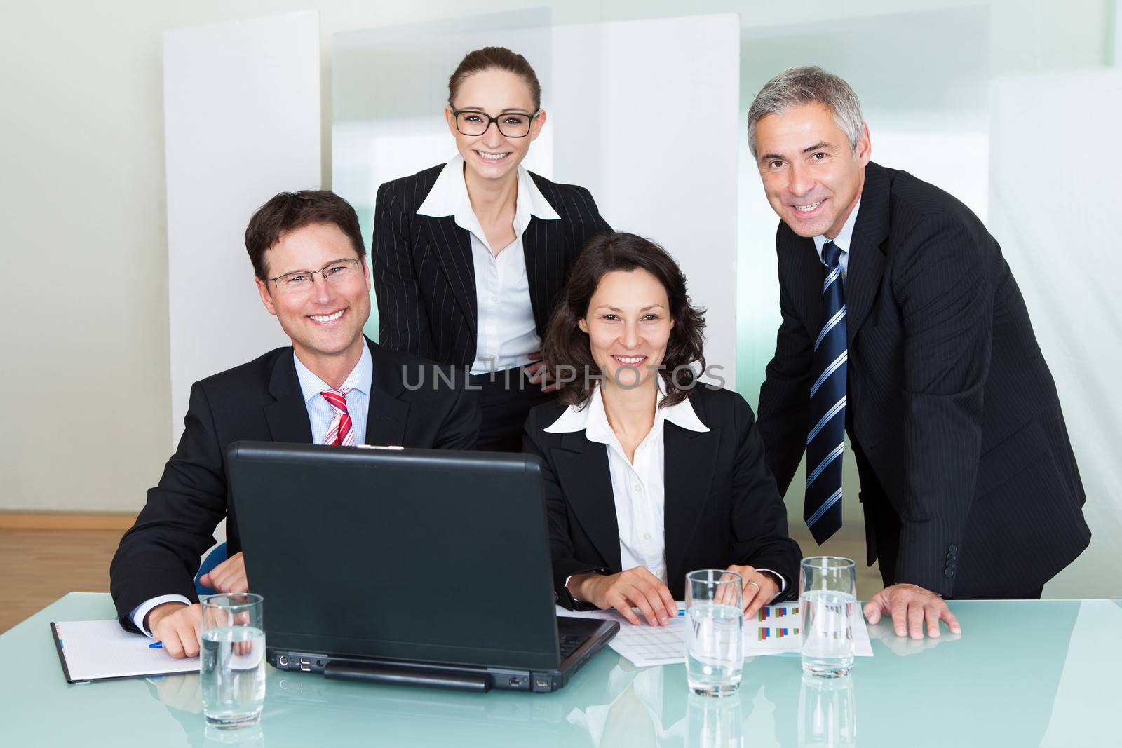 Confident successful business team of diverse executives posing in an office together smiling happily at the camera