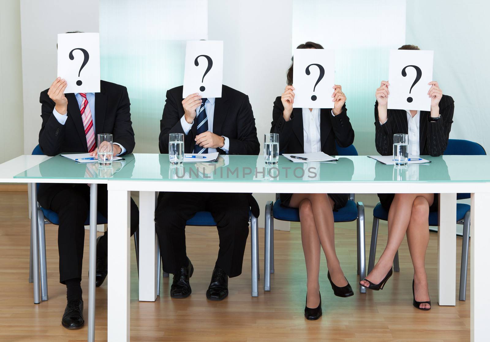 Row of businesspeople with question marks signs in front of their faces