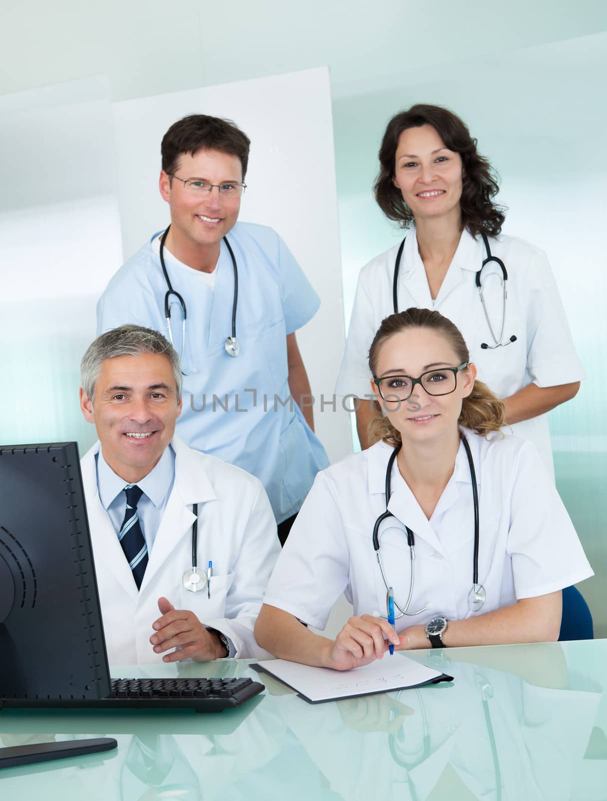Medical team comprising male and female doctors posing together in an office smiling at the camera