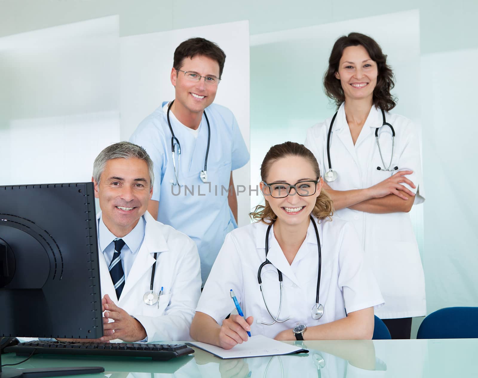 Medical team comprising male and female doctors posing together in an office smiling at the camera