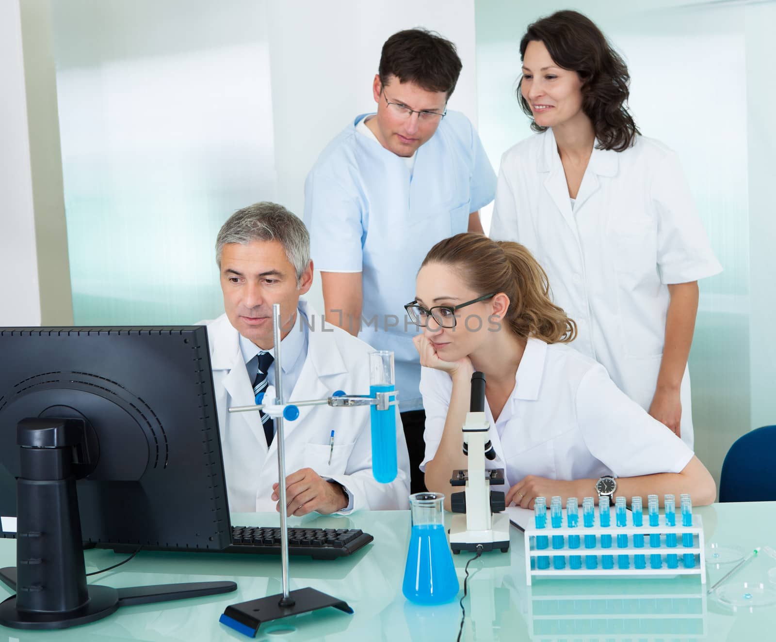 Paramedical or technical staff grouped together looking at a computer in a laboratory