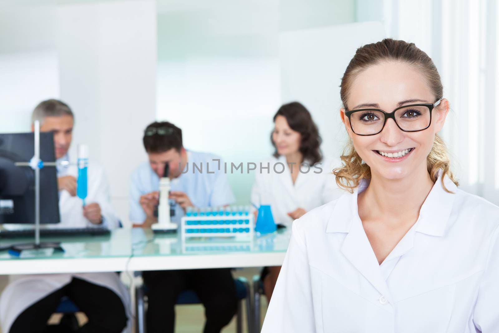 Attractive smiling female lab technician or technologist wearing glasses standing in the foreground