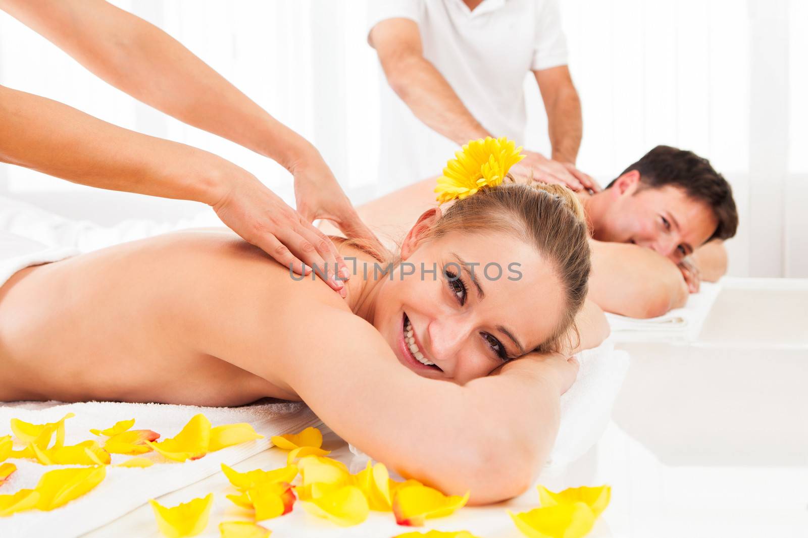 Attractive couple lying side by side in a spa enjoying the luxury of a deep tissue back massage together