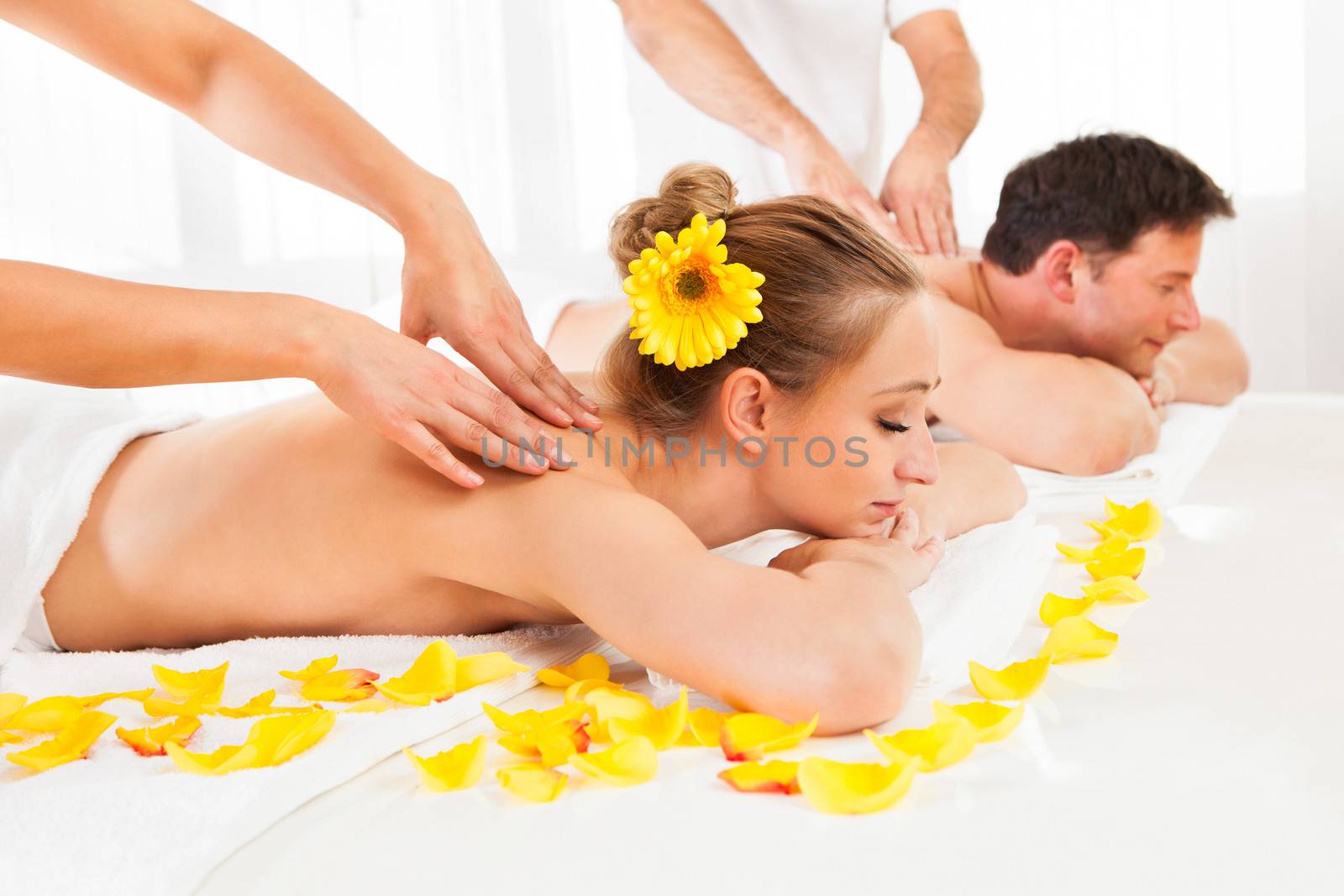 Attractive couple lying side by side in a spa enjoying the luxury of a deep tissue back massage together