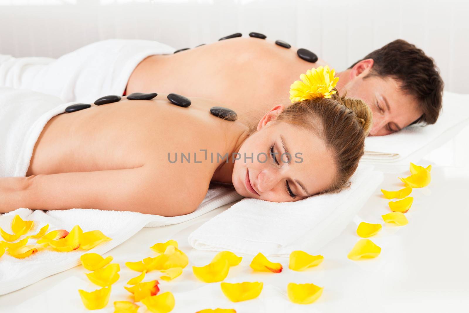 Couple having a hot stone massage treatment in a spa relaxing as the heat from the stones relaxes their muscles