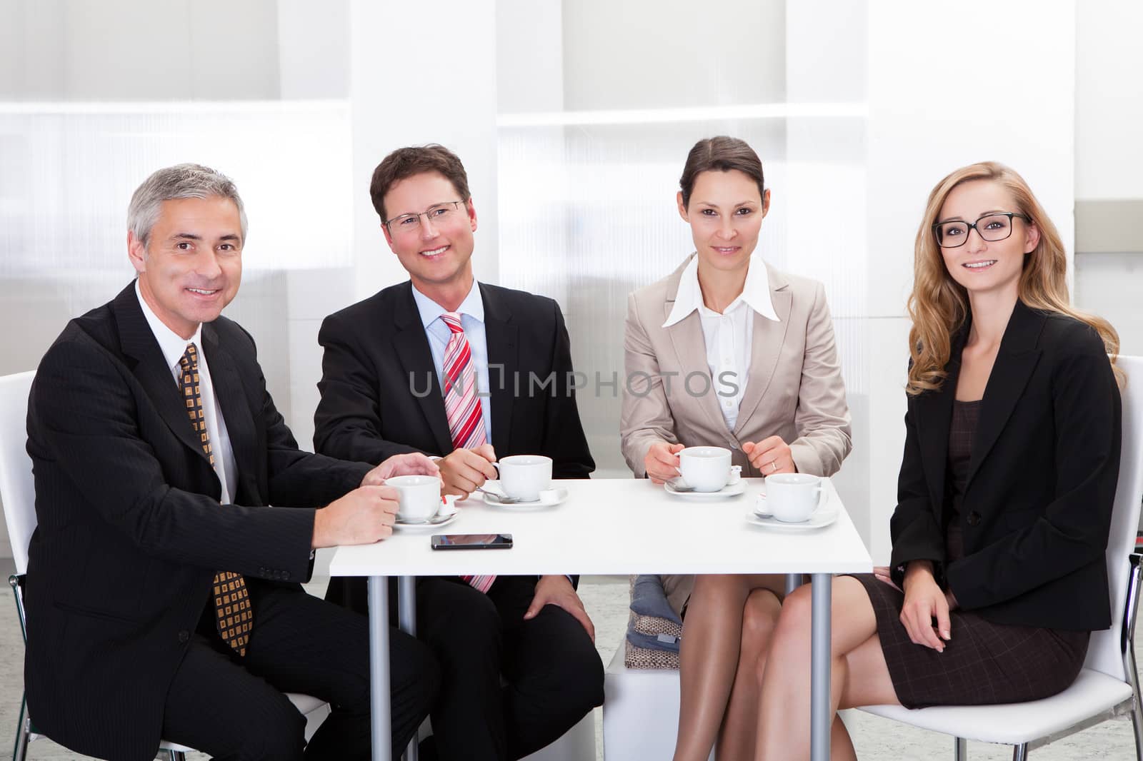 Business executives sitting around a table enjoying a relaxing cup of coffee together during a break