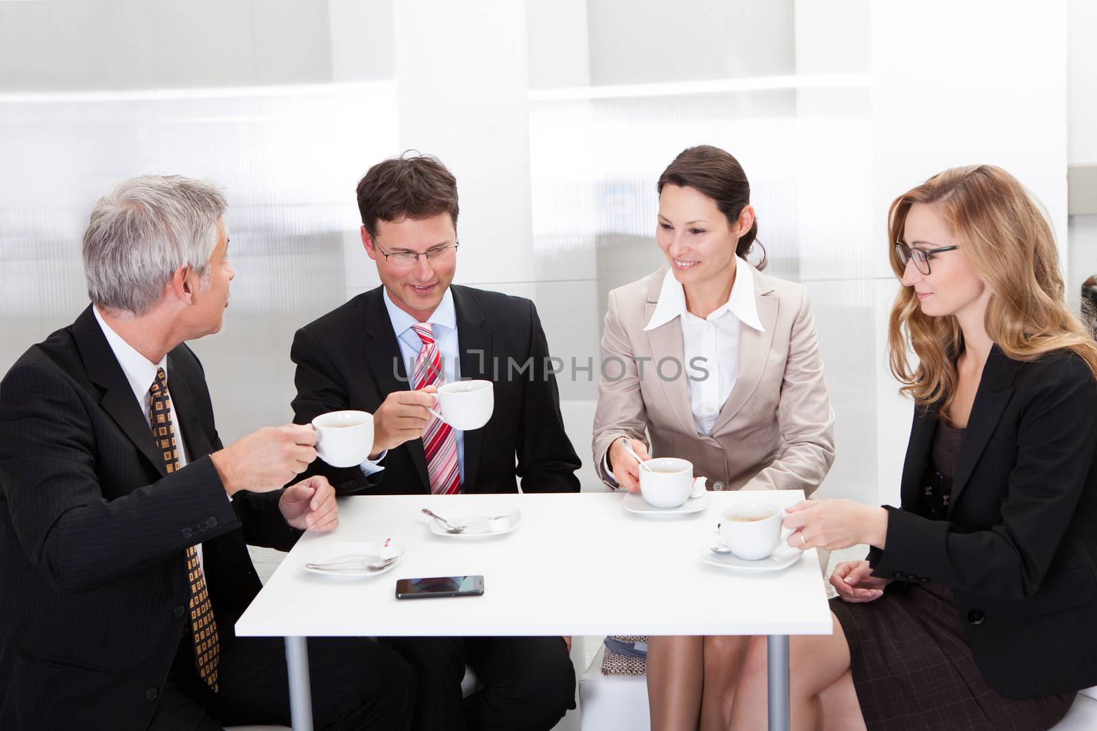 Business colleagues relaxing over coffee or having an impromptu meeting in the cafeteria