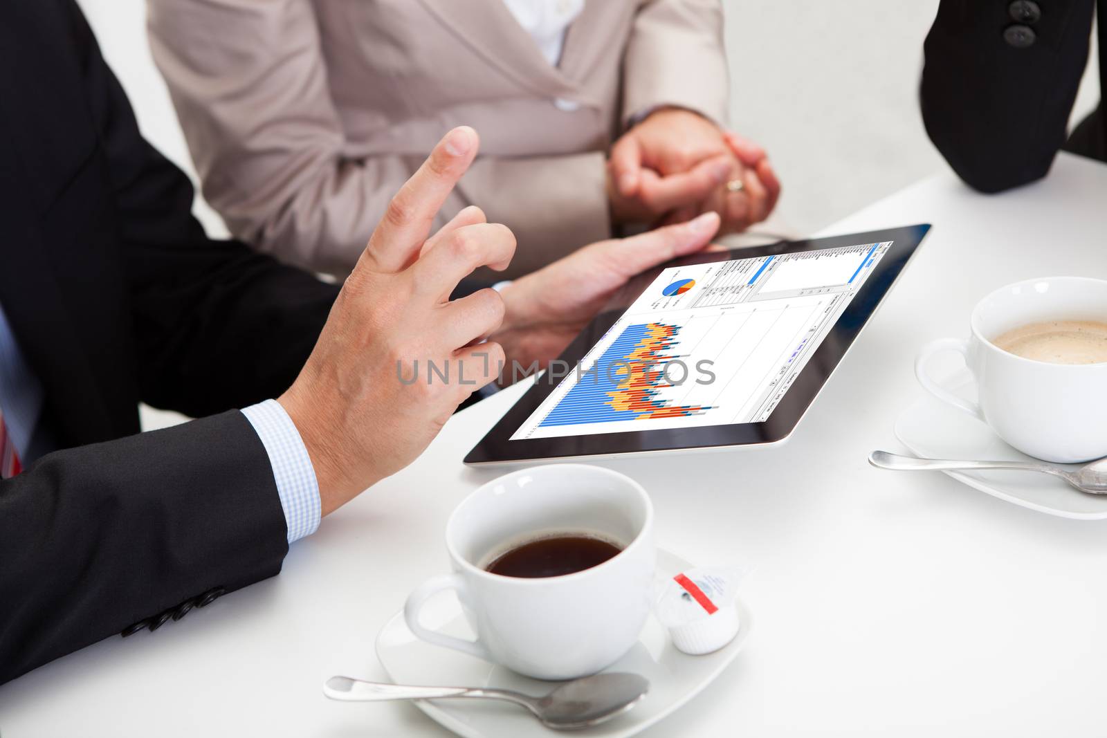 Business colleagues enjoying a coffee break smiling at something on the screen of a tablet held by one of the men