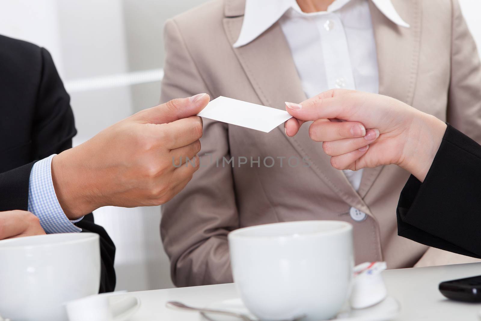 Businesspeople exchanging cards over coffee while having an informal meeting in a cafe