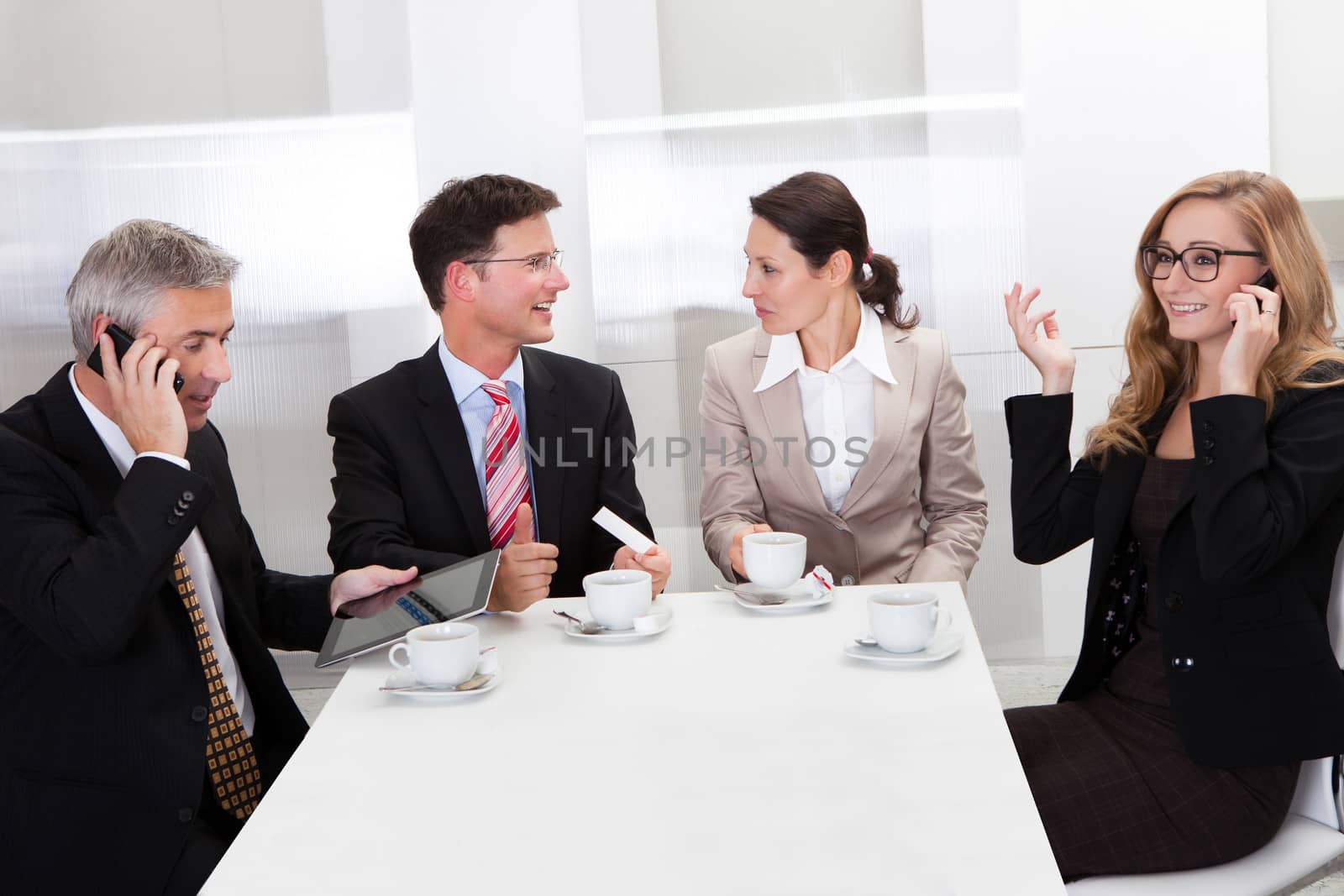 Business executives sitting around a table enjoying a relaxing cup of coffee together during a break