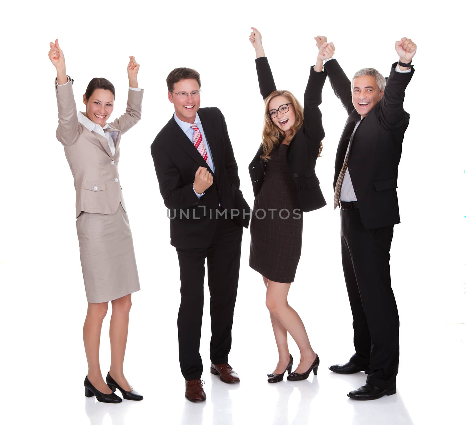 Four excited diverse professional businesspeople celebrating a success laughing and raising their arms in the air isolated on white