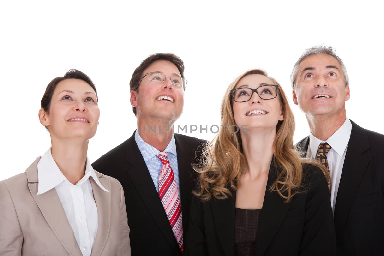 Four happy diverse professional business partners standing in a row looking upwards with a smile isolated on white