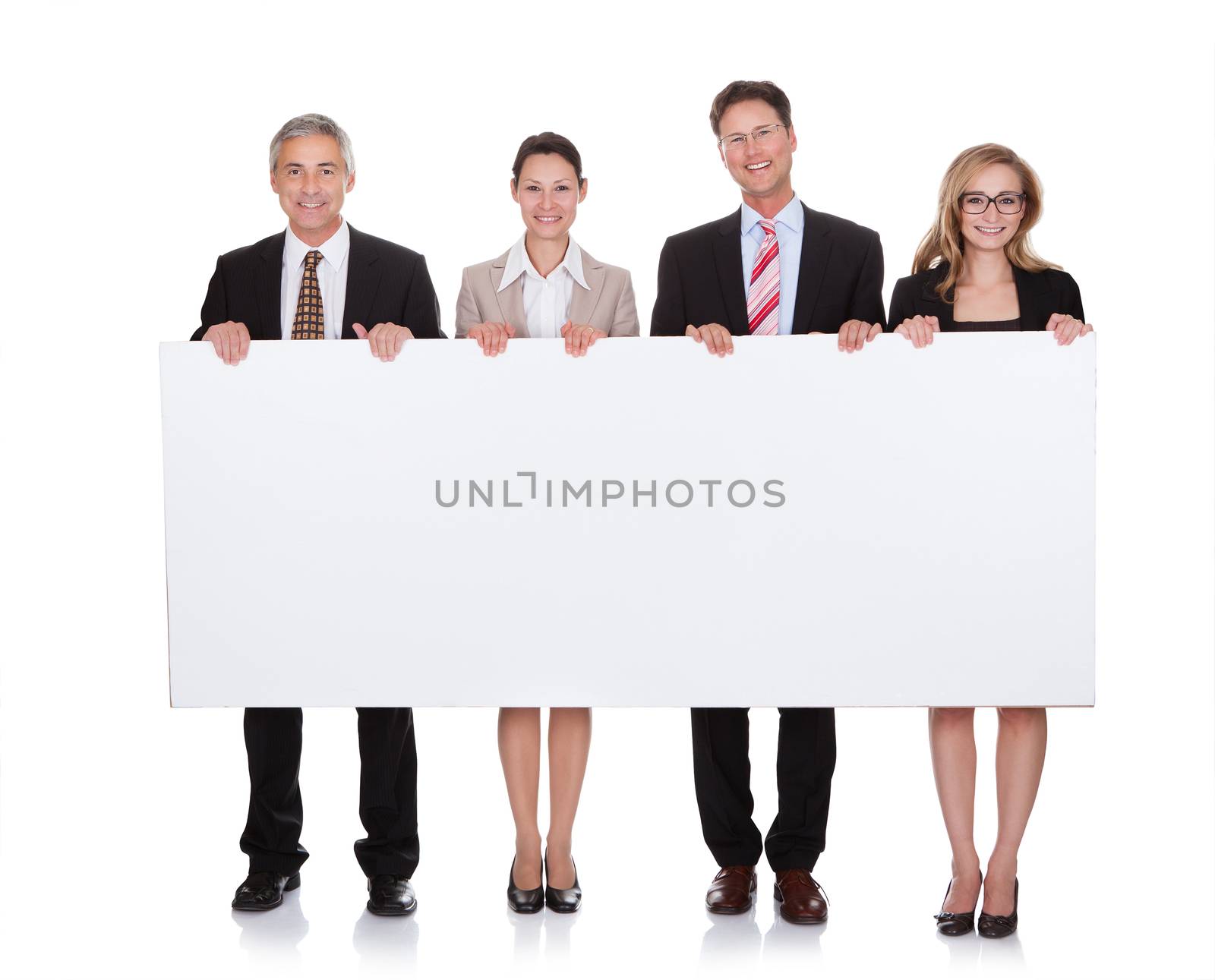 Four diverse professional businesspeople holding a blank banner or horizontal sign for your text or advertisement isolated on white