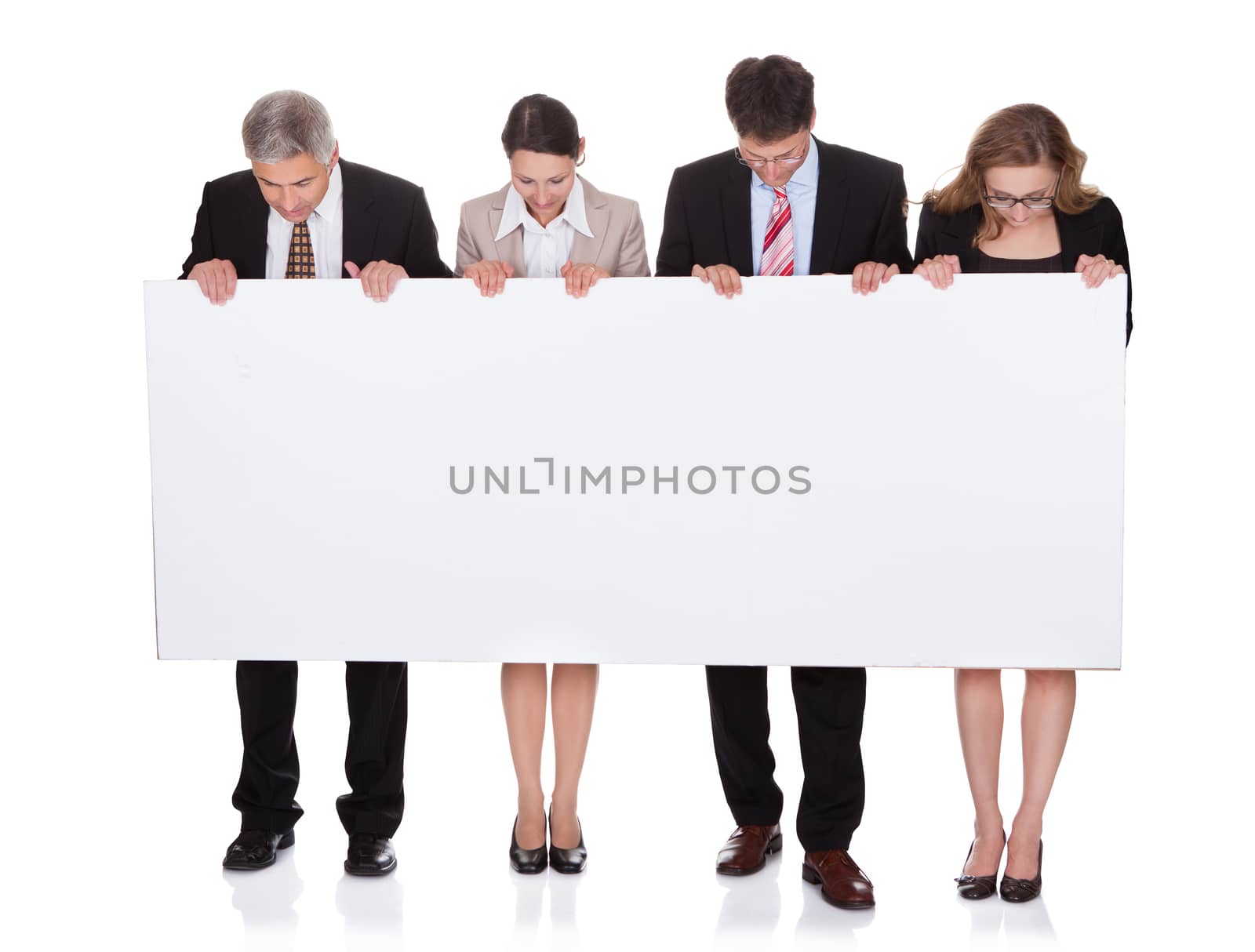 Four diverse professional businesspeople holding a blank banner or horizontal sign for your text or advertisement isolated on white