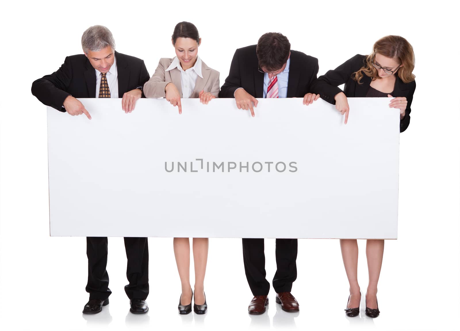 Four diverse professional businesspeople holding a blank banner or horizontal sign for your text or advertisement isolated on white