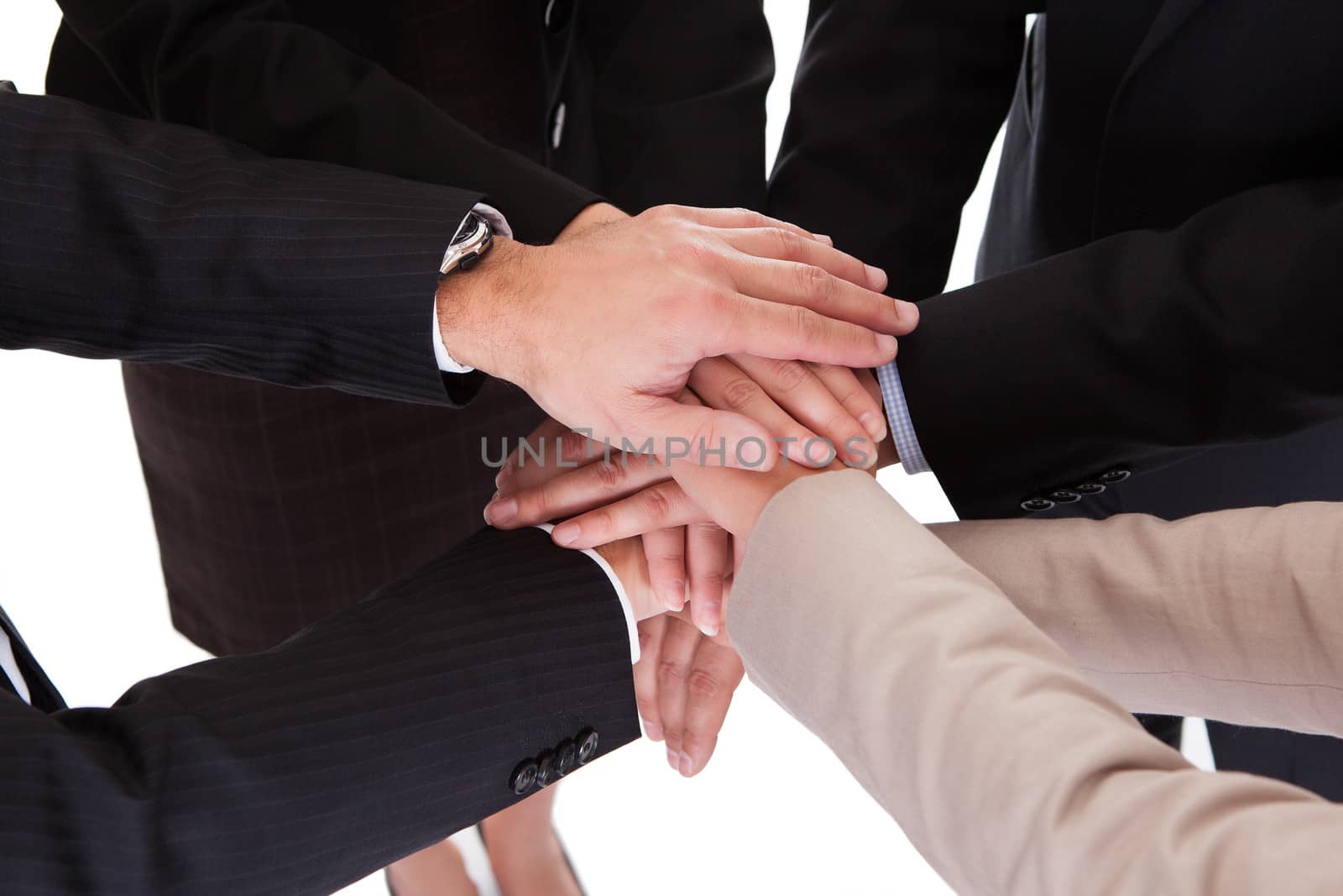 Group of four diverse businesspeople standing in a circle facing each other holding hands in a team