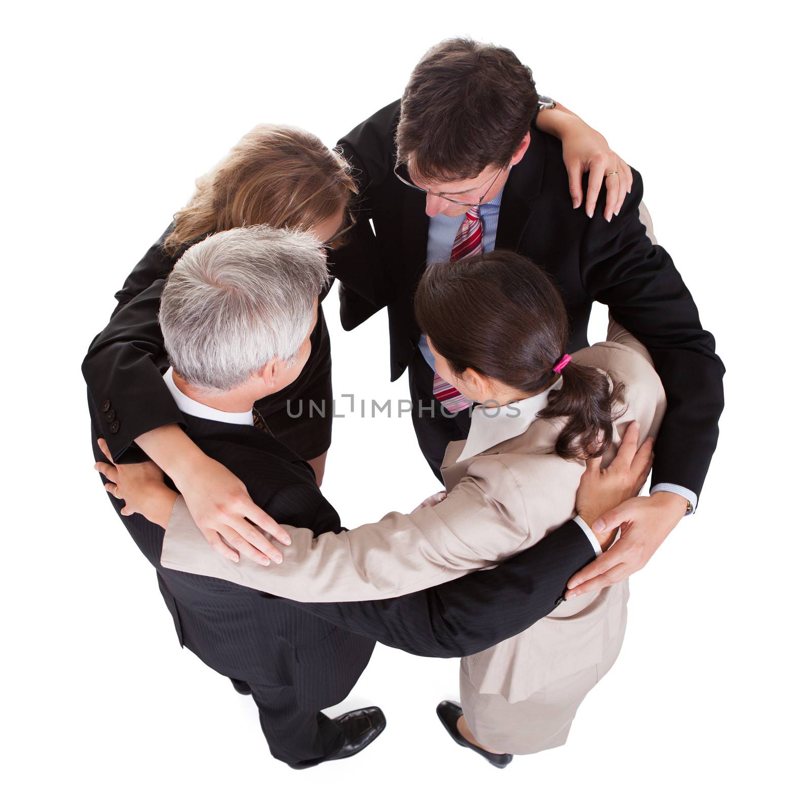 Group of four diverse businesspeople standing in a circle facing each other holding hands in a team