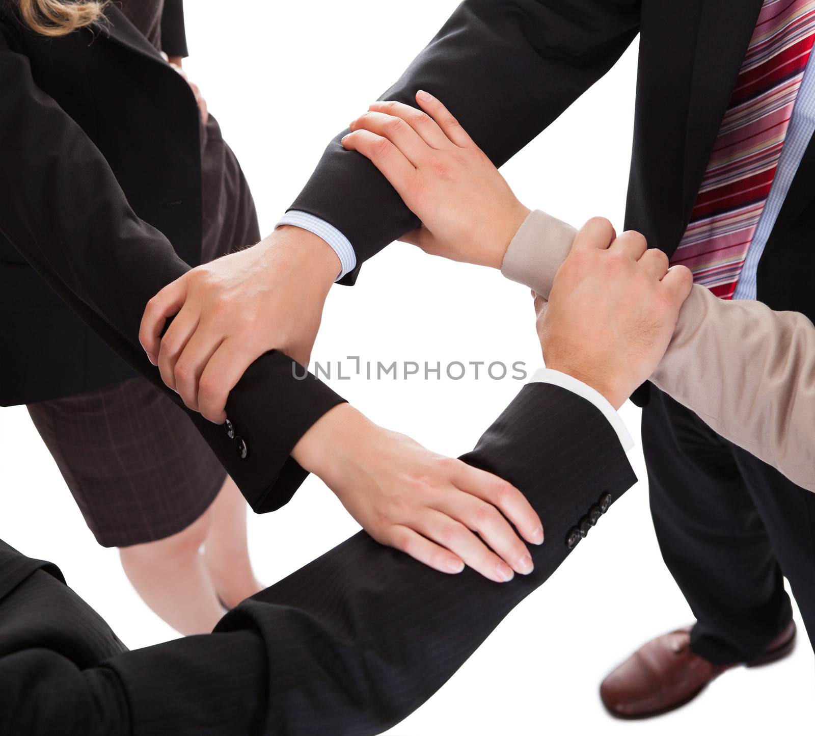 Cropped overhead view of a diverse group of businesspeople linking hands in a team