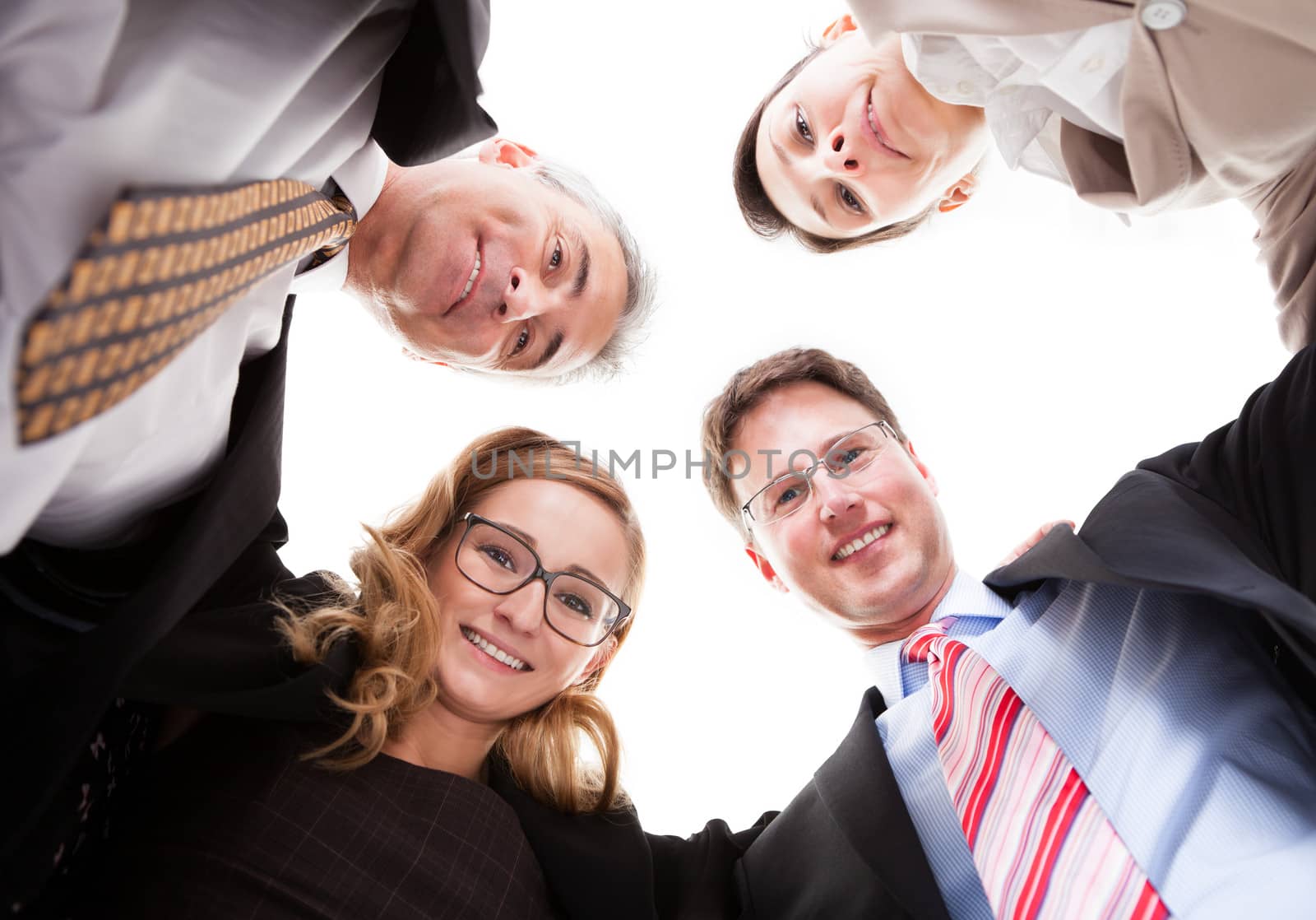 Low angle view of four diverse business executives looking down into the camera from above isolated on white