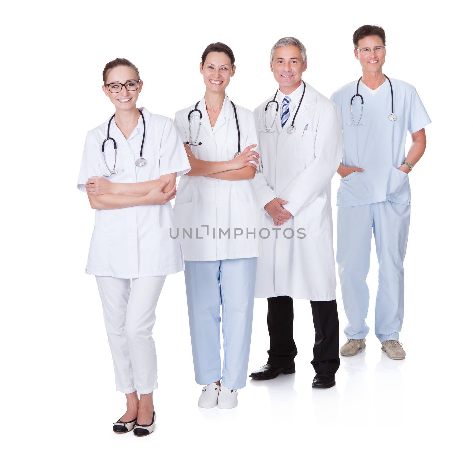 Row of smiling diverse medical doctors and nurses in white uniforms with stethoscopes standing in an oblique receding row isolated on white