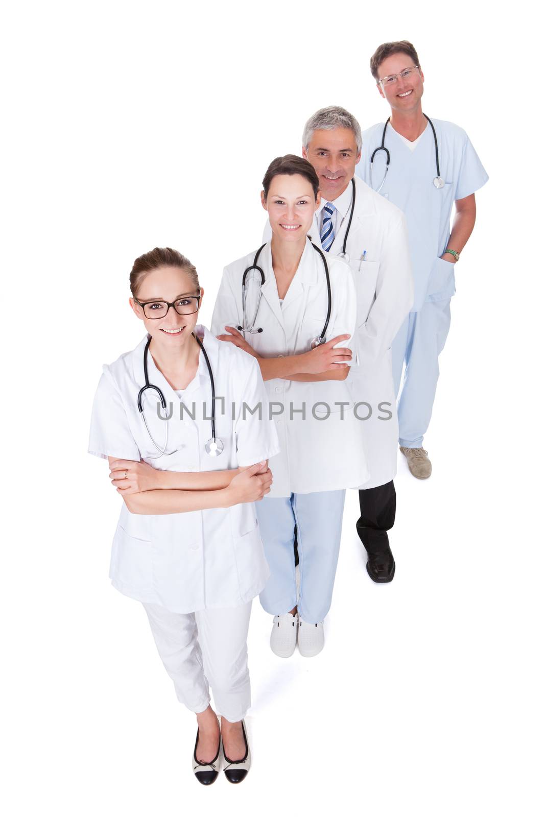 Row of smiling diverse medical doctors and nurses in white uniforms with stethoscopes standing in an oblique receding row isolated on white