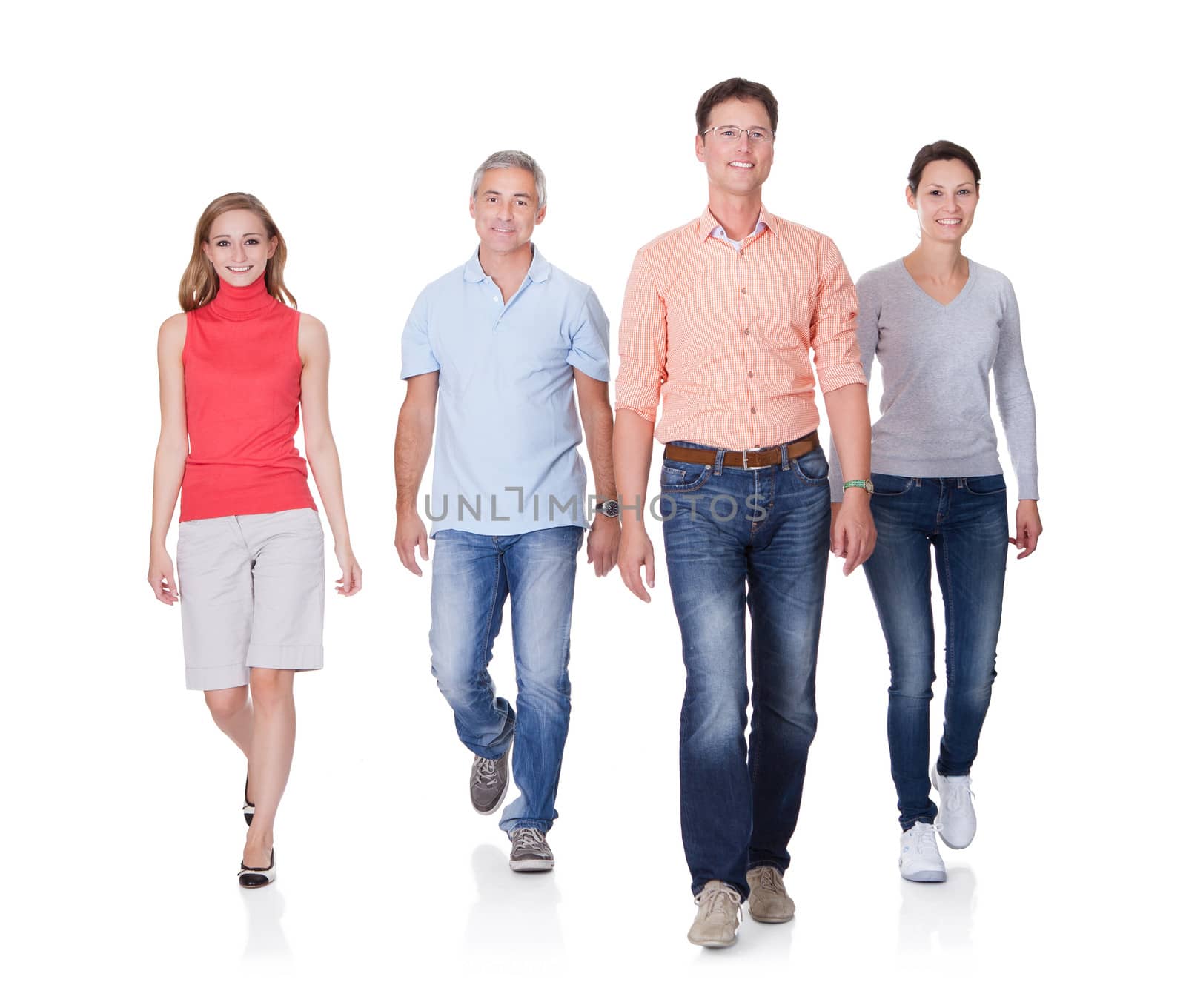 Group of four people wlaking towards camera. Isolated on white