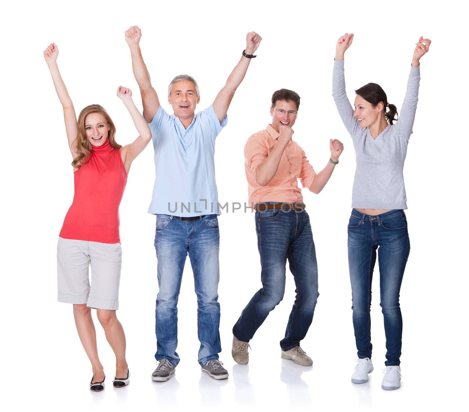 Two happy attractive couples in casual clothes and jeans celebrating raising their arms in the air and shouting on white