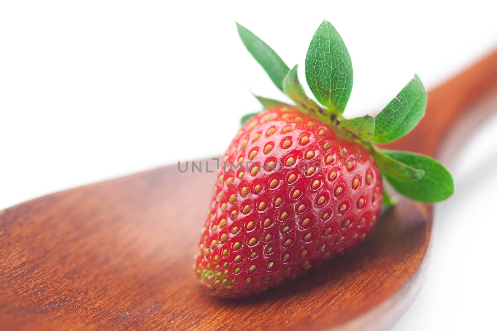 Beautiful ripe strawberry on a wooden spoon isolated on white
