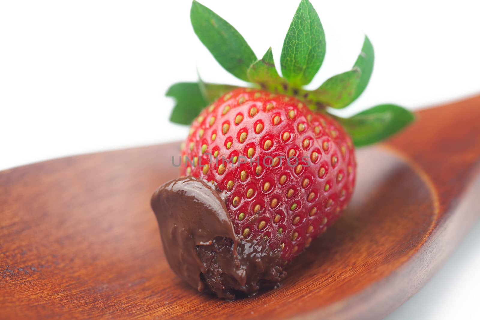 Beautiful ripe strawberries in chocolate on a wooden spoon isola by jannyjus