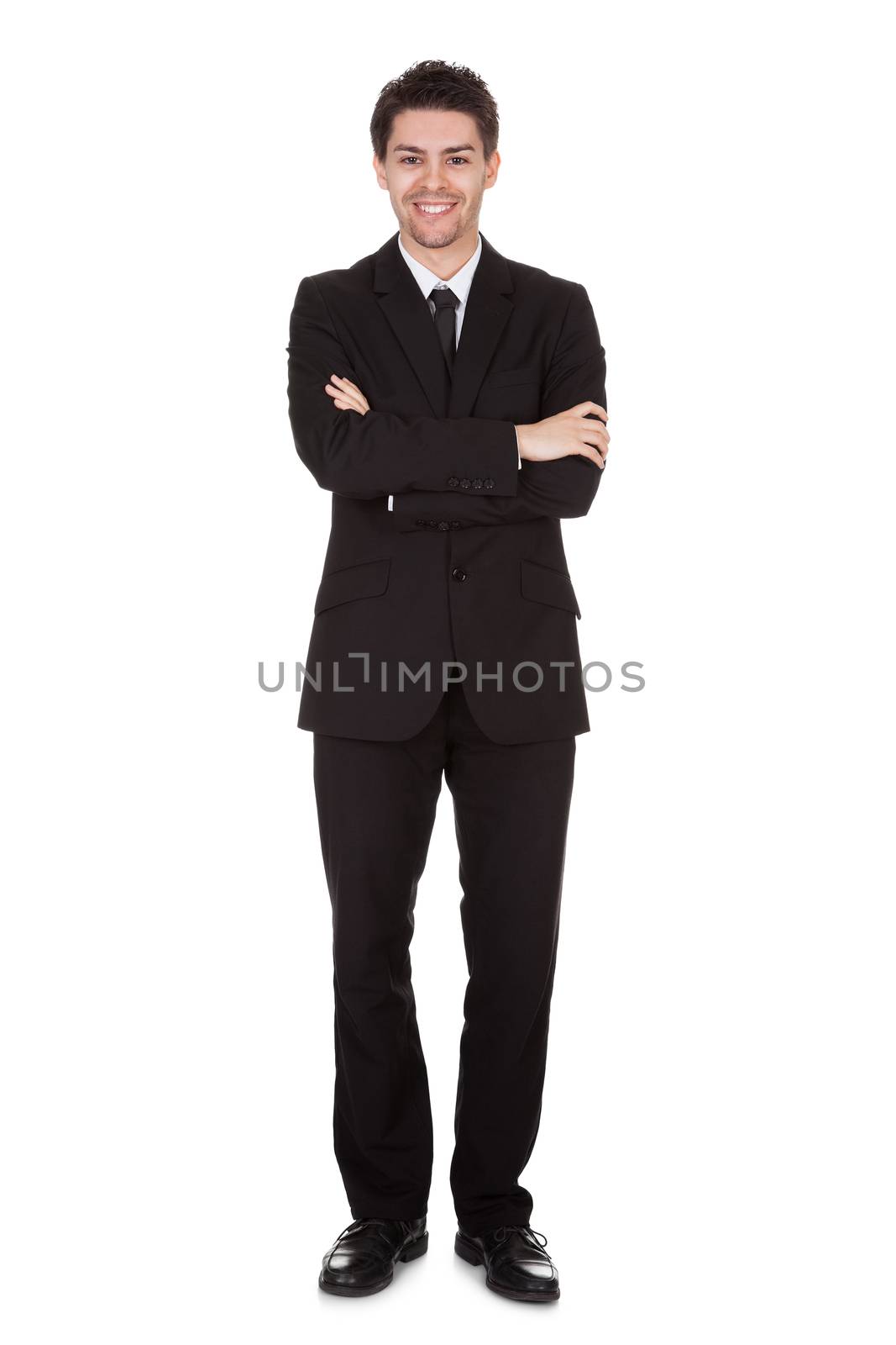 Businessman standing with folded arms by AndreyPopov