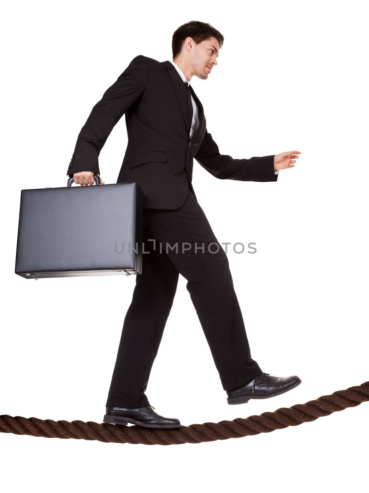 Conceptual image of a businessman carrying a briefcase balancing precariously as he walks a tightrope isolated on white